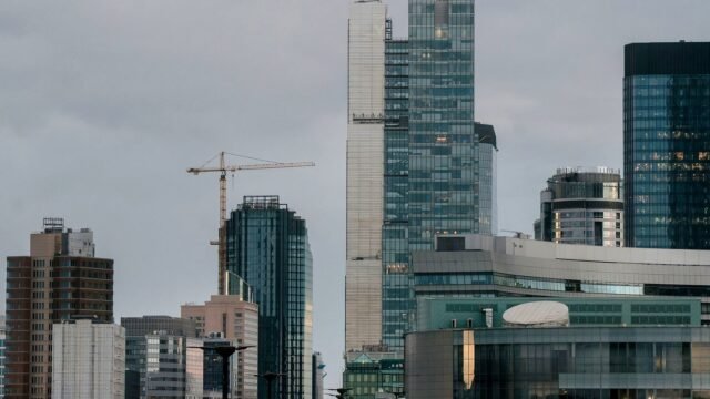 Panorama Warszawy z nowoczesnymi wieżowcami i dźwigami budowlanymi w ciągu dnia.
