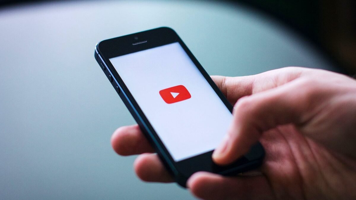 Zbliżenie dłoni z telefonem, na ekranie aplikacja YouTube.