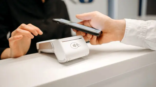 Płatność zbliżeniowa smartfonem przy kasie w sklepie