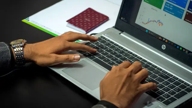 Dłonie na klawiaturze laptopa, na ekranie panel z wynikami kampanii reklamowych