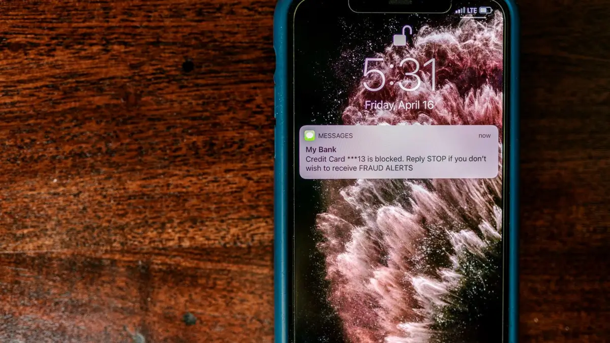 Smartfon na stole z ostrzeżeniem o oszustwie na ekranie