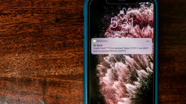 Smartfon na stole z ostrzeżeniem o oszustwie na ekranie