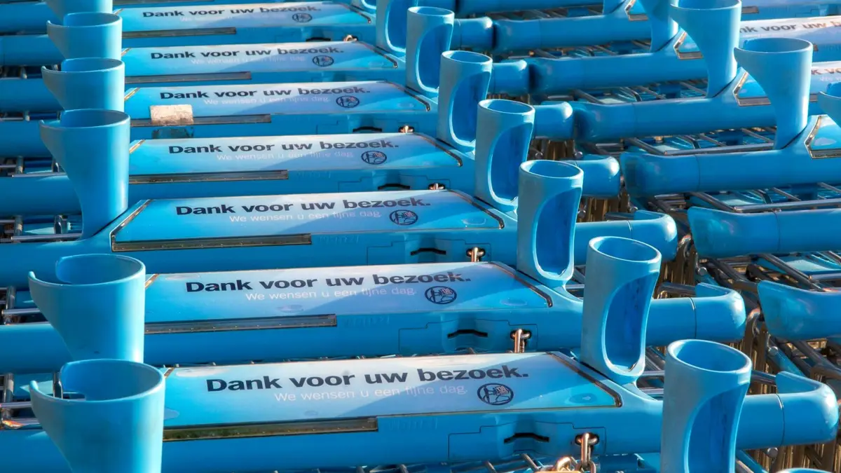 Rząd niebieskich wózków sklepowych Albert Heijn z napisem po niderlandzku