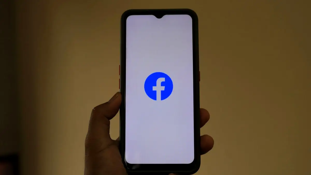 Dłoń trzymająca smartfon z logo Facebooka na ekranie