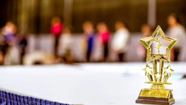 Złote trofeum w kształcie gwiazdy na stole, w tle rozmyte sylwetki ludzi