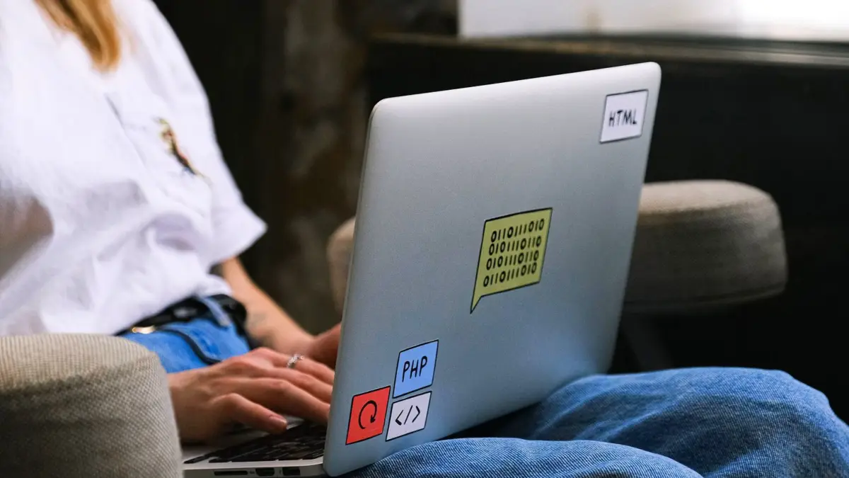 Laptop z naklejkami i fragmentem kodu na ekranie
