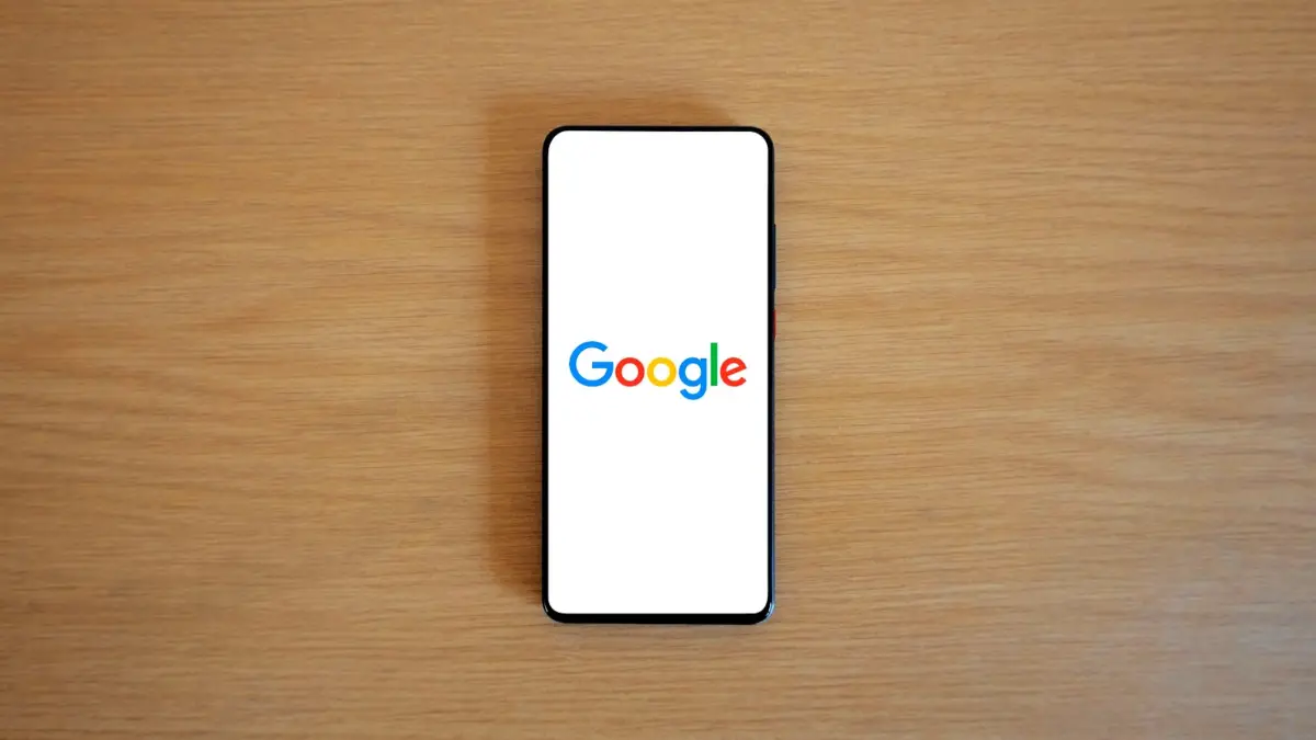 Smartfon ze stroną główną Google leżący na drewnianym blacie