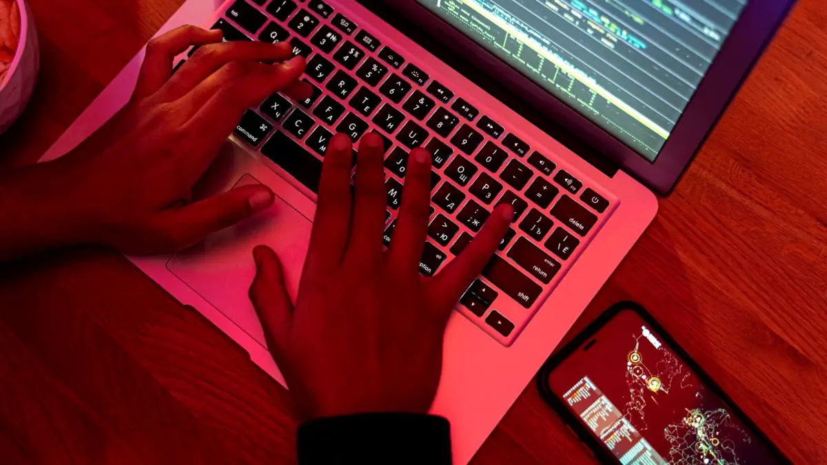 Dłonie na klawiaturze laptopa, na ekranie kod strony internetowej