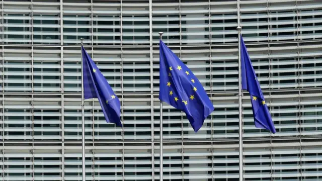Trzy flagi Unii Europejskiej przed budynkiem Komisji Europejskiej w Brukseli