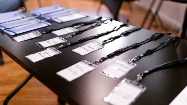 Identyfikatory z nazwiskami i teczki rozłożone na stole przed spotkaniem