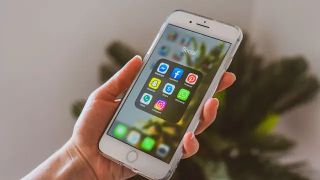 Dłoń trzymająca smartfon z ikonami aplikacji społecznościowych na ekranie