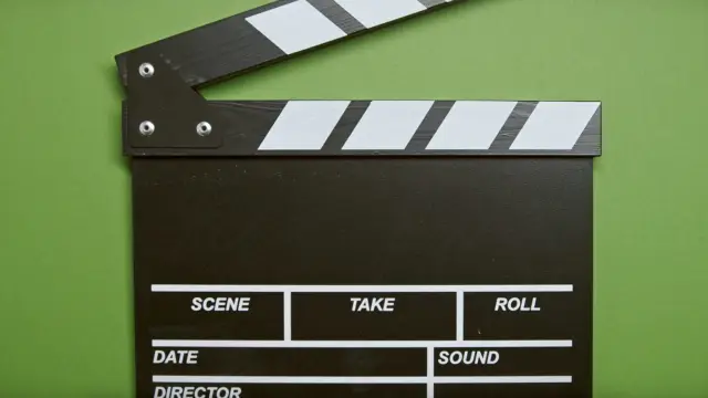 Klaps filmowy leżący na zielonym tle
