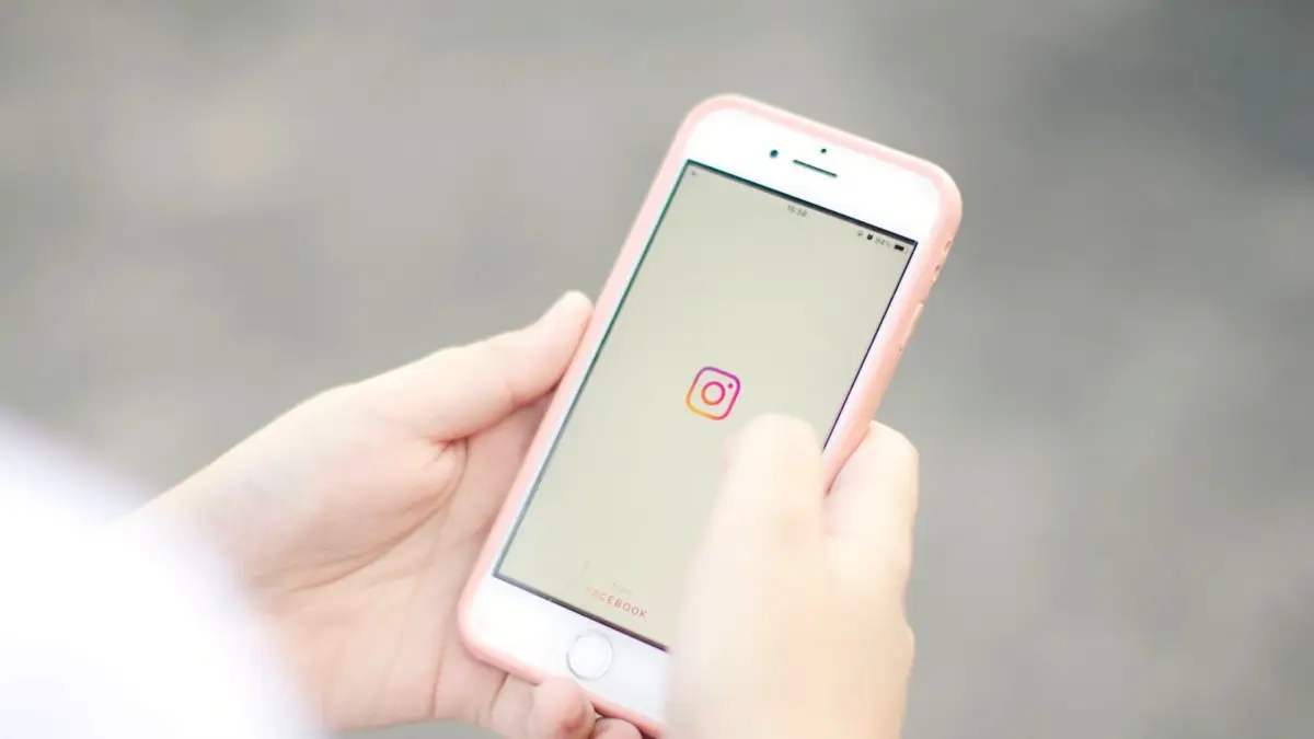 Dłonie trzymają smartfon z otwartą aplikacją Instagram