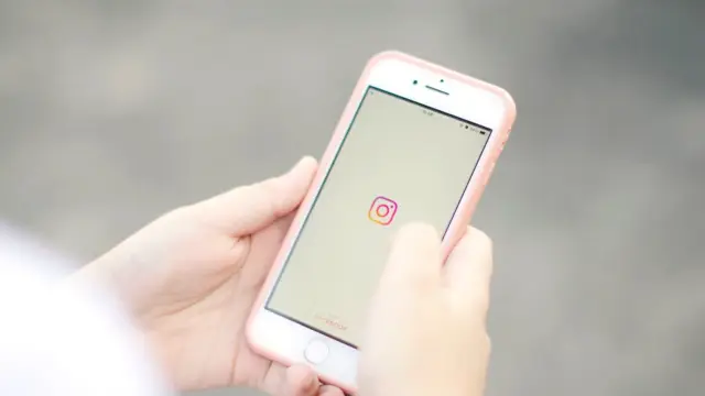 Dłonie trzymają smartfon z otwartą aplikacją Instagram