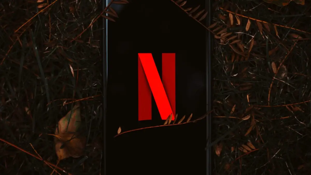 Smartfon z logo Netflix na ekranie leży na suchych liściach