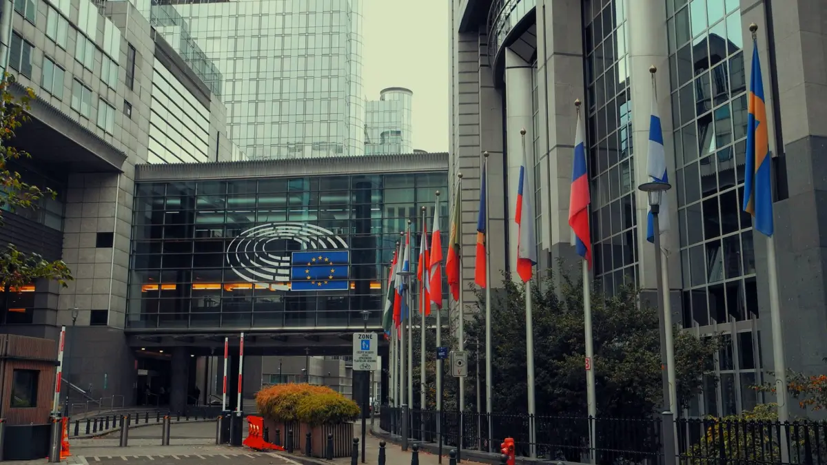 Budynek Parlamentu Europejskiego z rzędem flag Unii Europejskiej przed wejściem