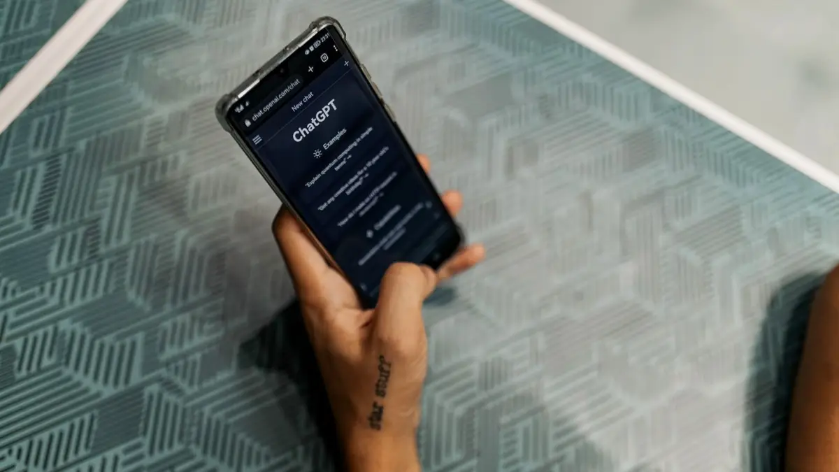 Dłoń trzyma smartfon z otwartą aplikacją ChatGPT
