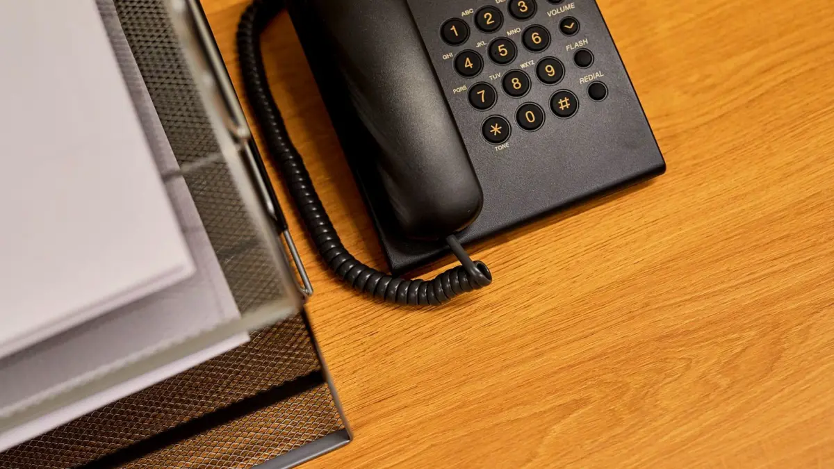 Czarny telefon stacjonarny na uporządkowanym biurku
