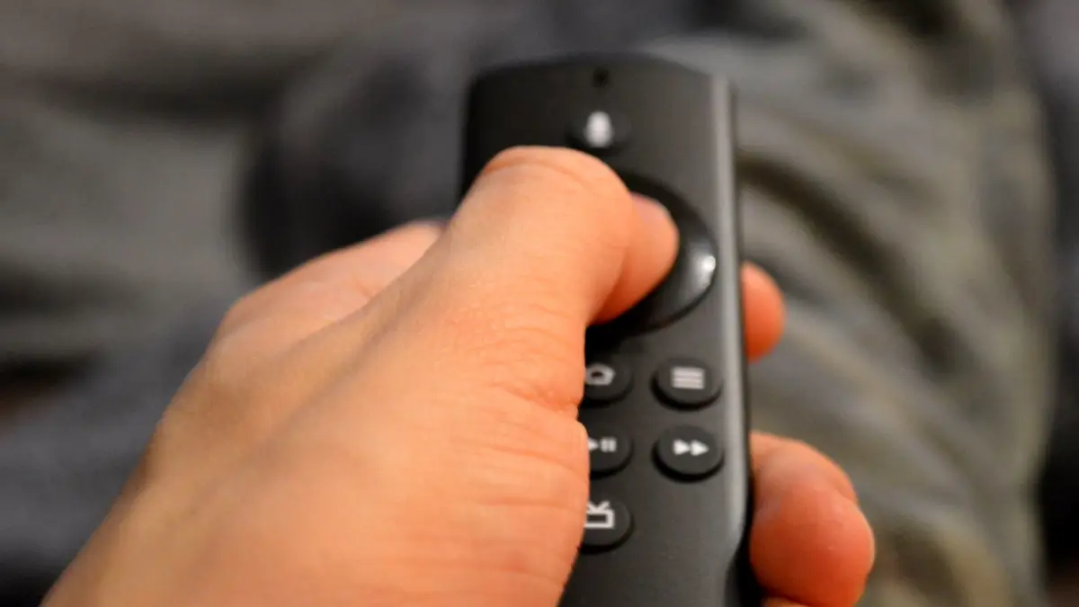 Zbliżenie dłoni trzymającej pilot do telewizora