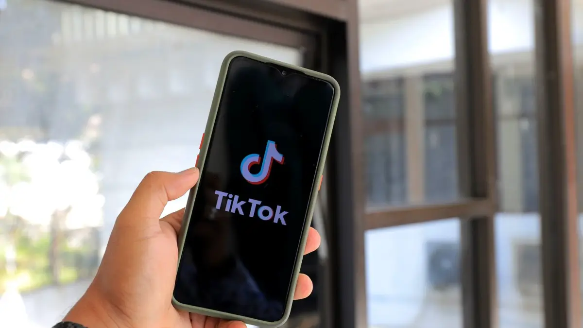 Dłoń trzyma smartfon z otwartą aplikacją TikTok