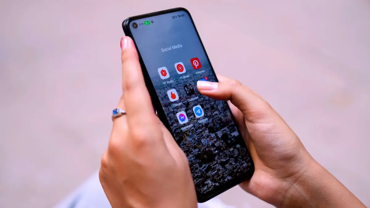 Dłonie trzymające smartfon z ikonami aplikacji społecznościowych na ekranie