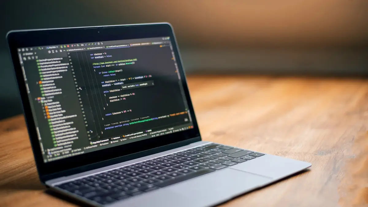 Laptop na drewnianym biurku z kodem strony internetowej na ekranie