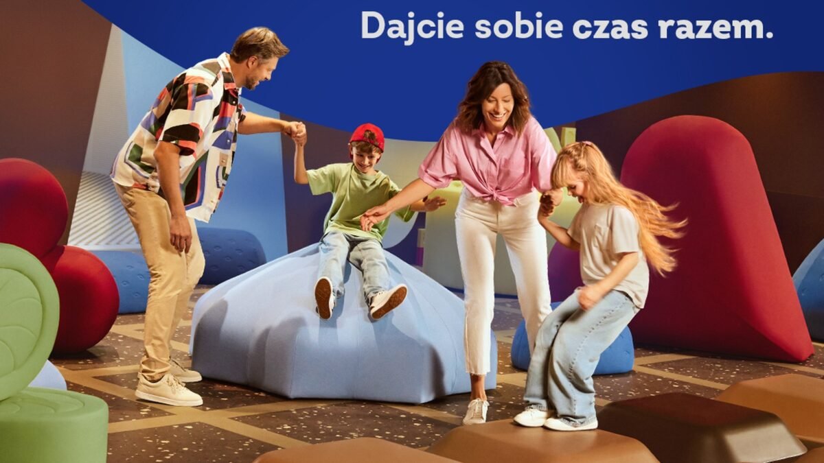 Rodzina bawi się w sali z kolorowymi bryłami, nad nimi hasło Dajcie sobie czas razem, kampania Wedla