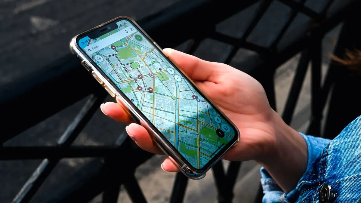 Dłoń trzymająca smartfon z otwartą aplikacją z mapą