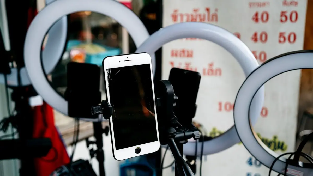 Smartfon na statywie między dwiema lampami pierścieniowymi