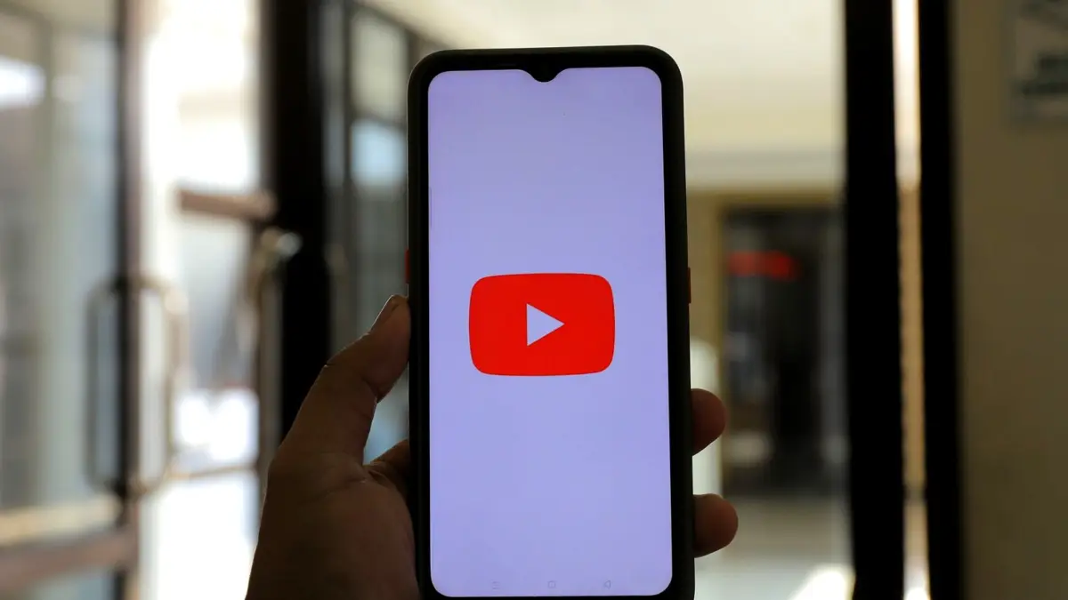 Dłoń trzyma telefon z otwartą aplikacją YouTube